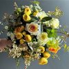Elegant hand-tied bouquet featuring peach, white, and spray roses with seasonal fillers in soft yellow and ivory tones.
